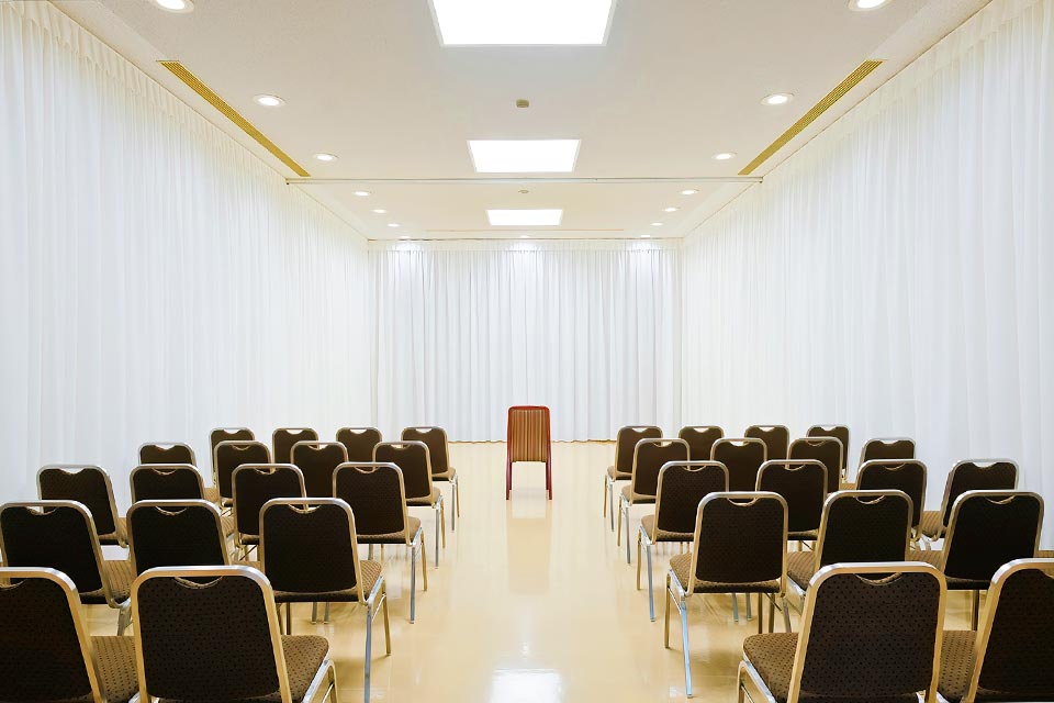 白いカーテンに包まれた清潔感あふれる町屋斎場の葬儀式場