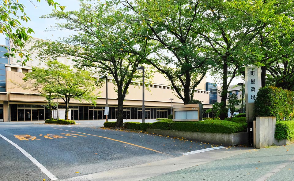 樹木越しに望む町屋斎場の建物外観と施設看板の全景